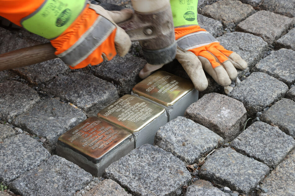 Ein Mitarbeiter des städtischen Bauhofes verlegt auf dem Gehweg der Ludwig-Kirsch-Straße Stolpersteine.