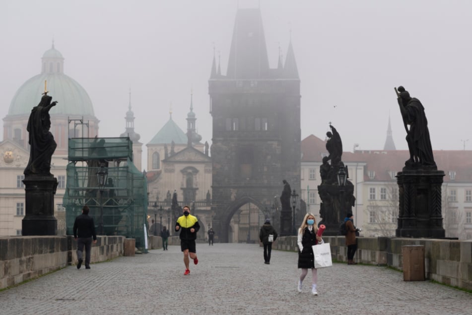 Nebel liegt über der Karlsbrücke, über die nur wenige Passanten gehen.