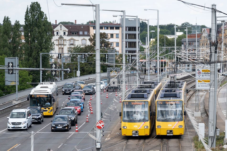 Zwei Stadtbahnen fahren neben Autos und einem Bus.