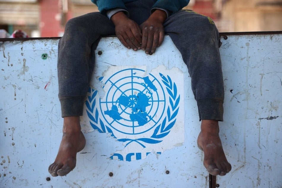 A Palestinian boy sits over a torn UNRWA sticker in Nuseirat in the central Gaza Strip.