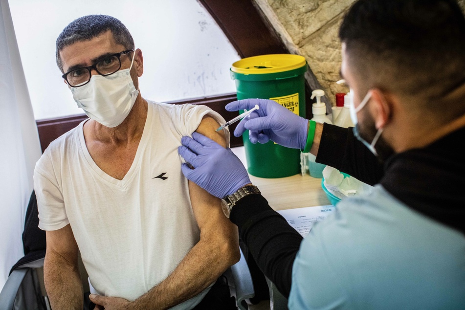 Ein Mann erhält von einem medizinischem Mitarbeiter in einem Impfzentrum in Jerusalem eine Impfung gegen das Coronavirus.