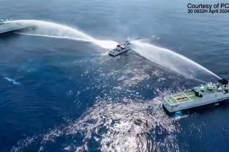 A screen grab from video released on April 30, 2024, shows the Philippine Coast Guard ship BRP Bagacay (c.) being hit by water cannons from Chinese coast guard vessels near the Scarborough Shoal.