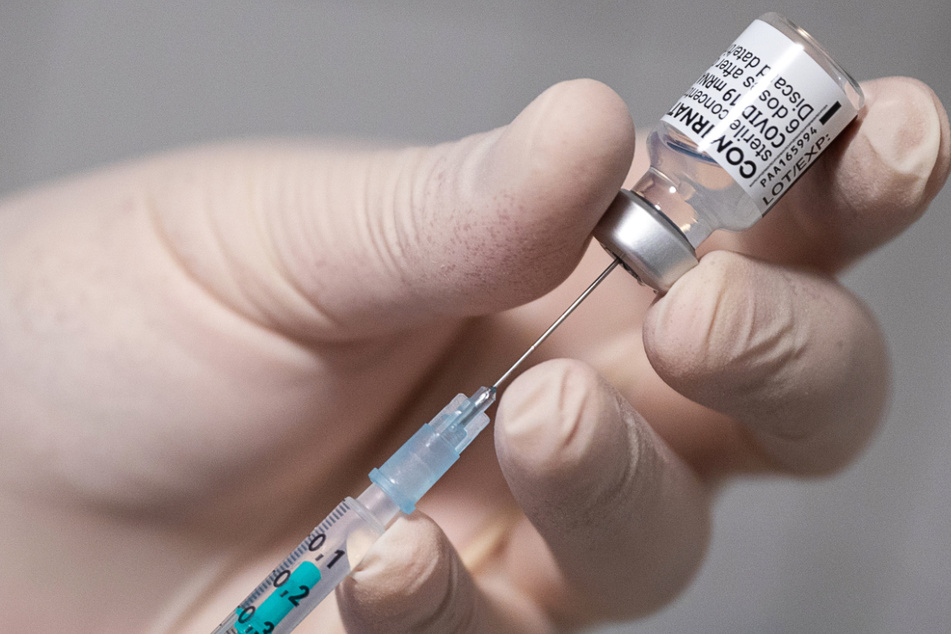 Ein Arzt zieht in einer Hausarztpraxis eine Spritze mit dem Impfstoff von Pfizer/Biontech auf.