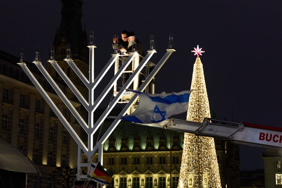 Andreas Dressel (l, SPD) und Shlomo Bistritzky entzünden zusammen den Chanukka Leuchter auf der Reesendammbrücke am Jungfernstieg an.