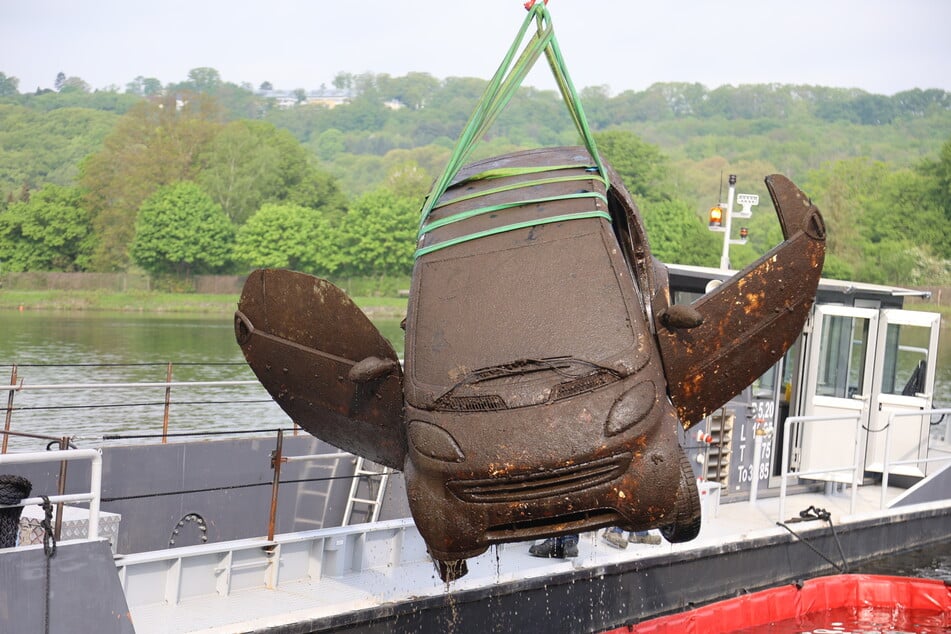 Ein Kran zieht ein mit Schlamm bedecktes Auto aus dem Baldeneysee in Essen. Insgesamt wurden vier Fahrzeuge in dem Ruhr-Stausee gefunden.