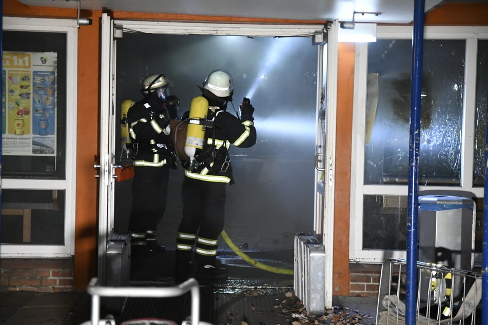 Feuerwehrleute stehen im Eingang der Schule am Denksteinweg.
