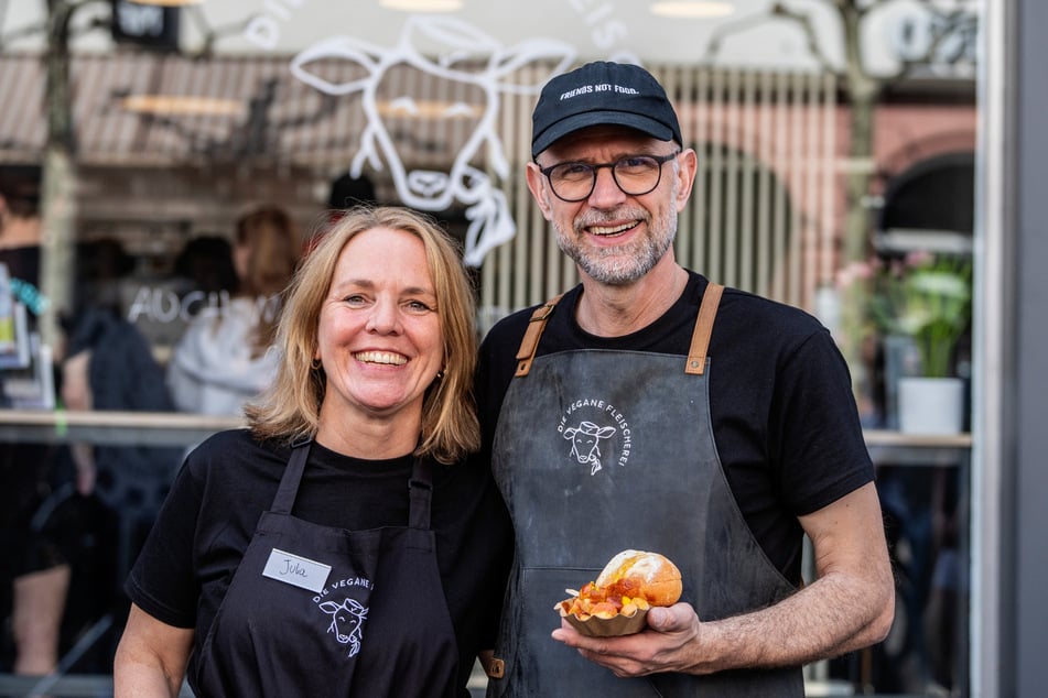Die Mainzer Filialbetreiber Julia und Christian Rubin stehen mit einer veganen Currywurst-Alternative vor ihrem Geschäft.