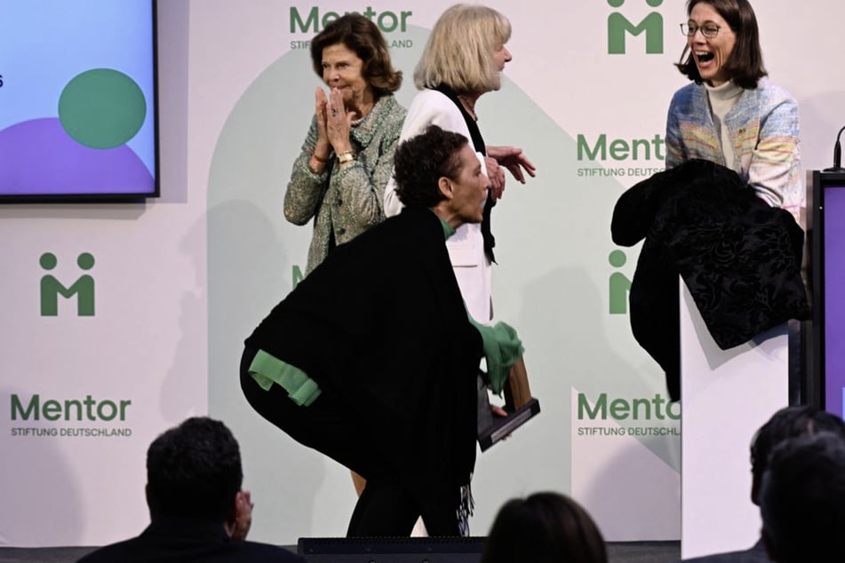 Königin Silvia von Schweden (82, l.) und Bettina Gräfin Bernadotte (52, r.) schauen zu, wie Sybille Perez (2.v.l.), Leiterin der Mentor-Akademie, den Preis wieder aufhebt, der auf den Boden gefallen ist. Bei dem Sturz ist der Preis der Preisträgerin Monika Brandt (3.v.l.) auf den Zeh gefallen.