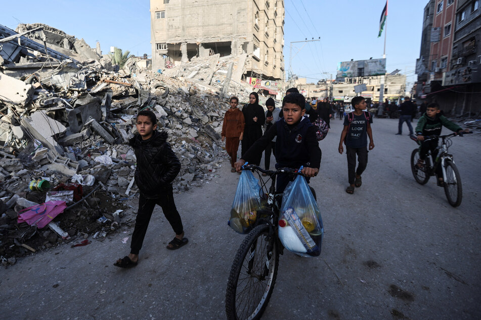 Displaced Palestinian children ride bicycles and walk on a street during a temporary pause, in Khan Younis in the southern Gaza Strip, on November 24, 2023.