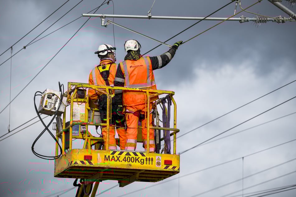 Zwei Arbeiter treiben die Elektrifizierung voran.
