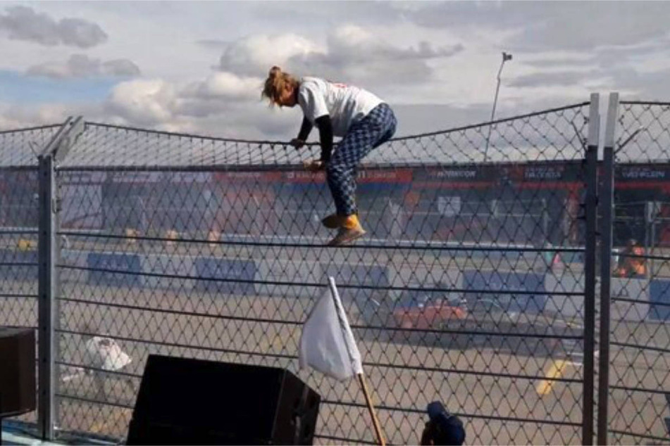 Eine Aktivistin der "Letzten Generation" erklimmt den Zaun entlang der Rennstrecke für das Formel-E-Rennen in Berlin.