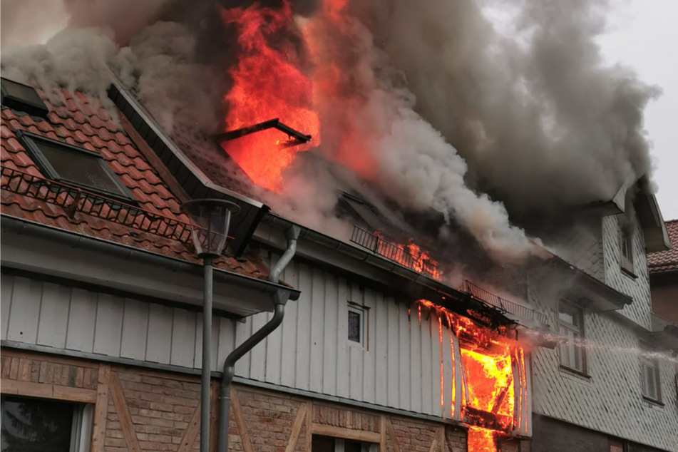 Flammen schlagen aus einem Fenster des in Brand geratenen Wohnhauses.