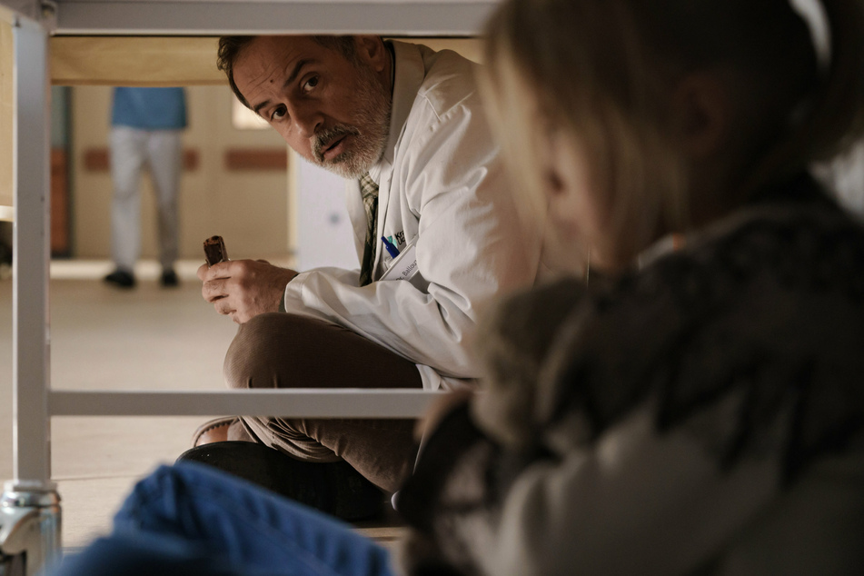 Doktor Ballouz (Merab Ninidze, 55) setzt sich zu Flori (Mavie Meschkowski) unter den Tisch in einer Szene der sechsteiligen ZDF-Reihe "Doktor Ballouz".