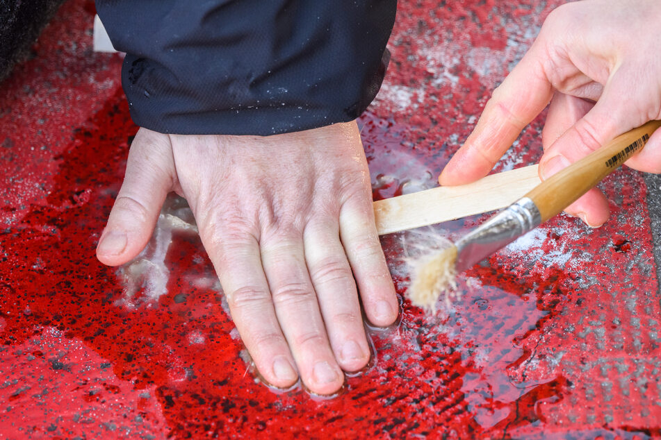 Die festgeklebte Hand einer Aktivistin wird mithilfe von Speiseöl gelöst.