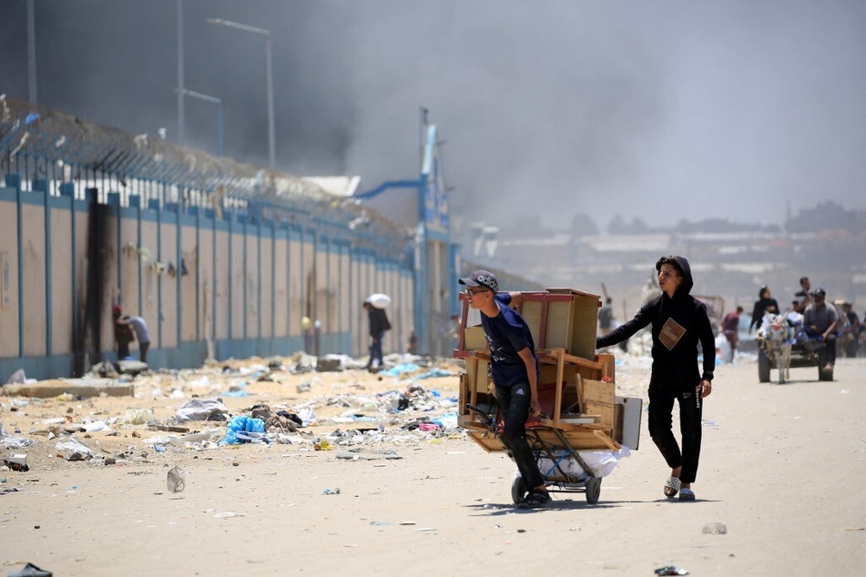 Palestinians flee with their belongings as smoke rises following Israeli attacks in the Tal al-Sultan neighborhood in Rafah in the southern Gaza Strip.