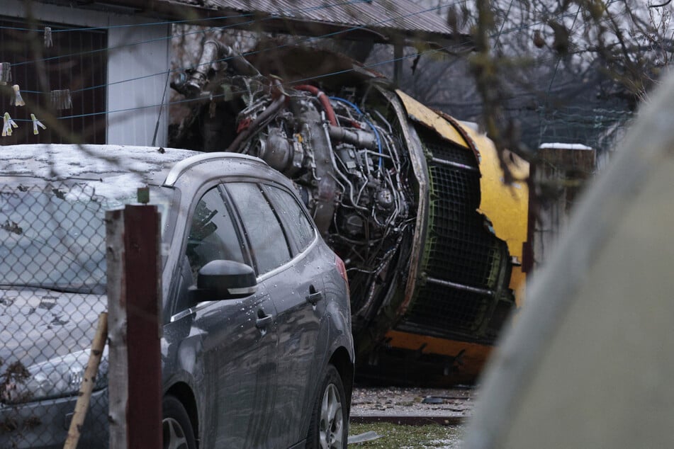 Ein Teil des abgestürzten Flugzeugs liegt neben einem Auto.