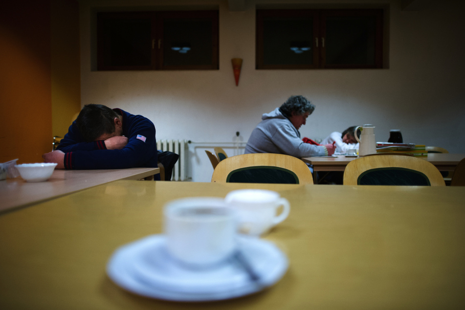 Ein Besucher des Nachtcafés der St. Petrus Gemeinde in Dresden-Strehlen liegt im Aufenthaltsraum mit dem Kopf auf dem Tisch und ruht sich aus.