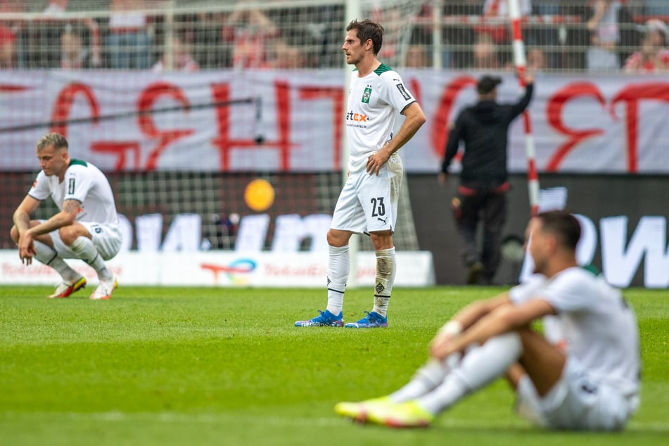 Jonas Hofmann (M.) steht enttäuscht auf dem Spielfeld, während seine Kollegen Jordan Beyer (21, l.) und Ramy Bensebaini (26) konsterniert zu Boden gegangen sind.
