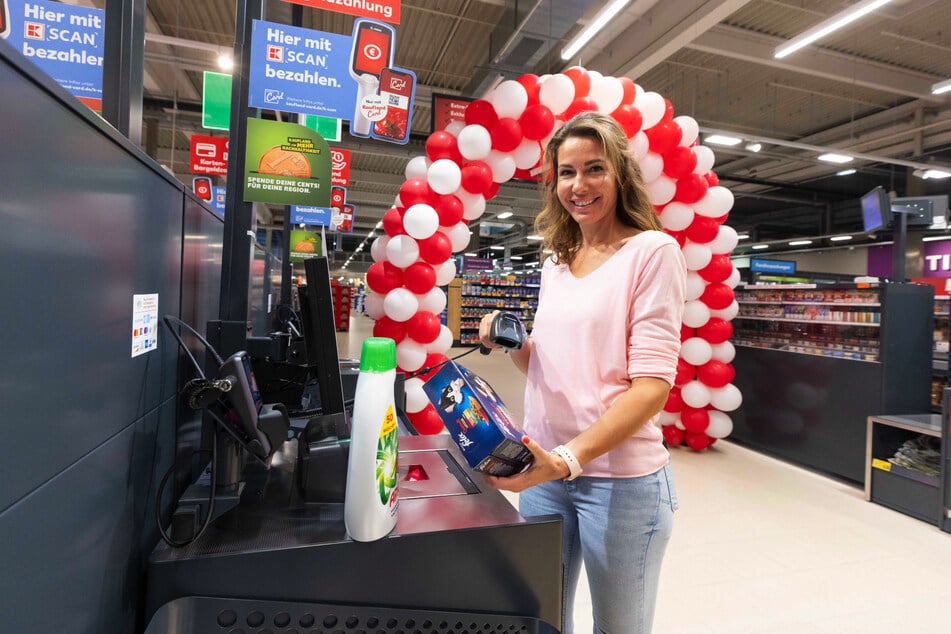 Neben herkömmlichen Bandkassen können Kunden ihren Einkauf an den SB-Kassen auch selbst scannen. Mitarbeiterin Anne Berger zeigt, wie es geht.