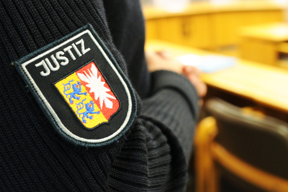 Ein schleswig-holsteinischer Justizbeamter steht im Landgericht im Sitzungssaal. (Symbolbild)