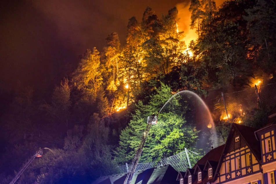 Die Feuerwehr versuchte die lodernden Flammen direkt hinter Häusern im Nationalpark Böhmische Schweiz zu löschen.