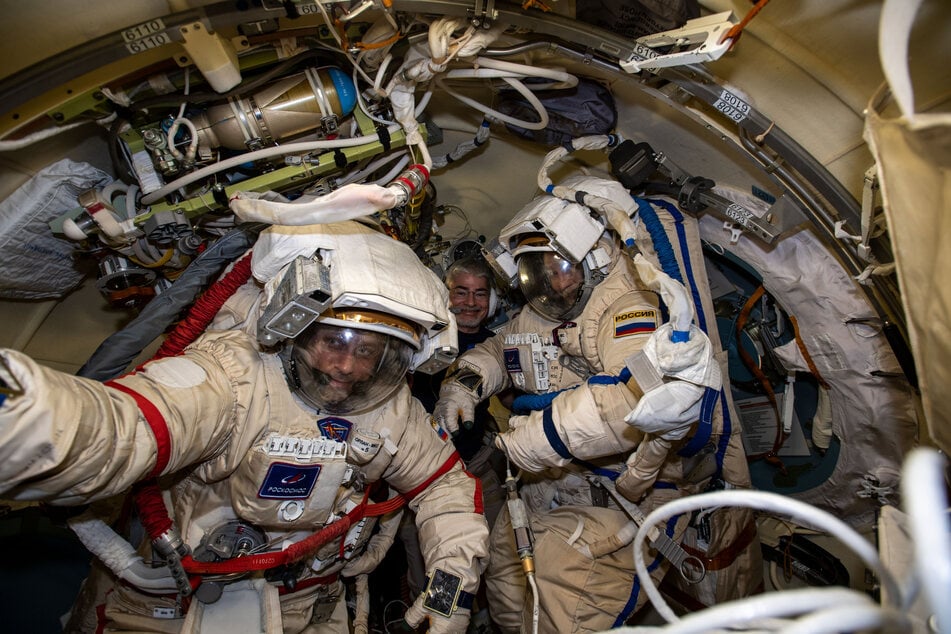 Die Kosmonauten Anton Schkaplerow (l) und Pjotr Dubrow (r) bereiten sich in ihren russischen Orlan-Raumanzügen mit Unterstützung des NASA-Astronauten Mark Vande Hei (hinten) auf einen bevorstehenden Weltraumspaziergang an der Internationalen Raumstation ISS vor.