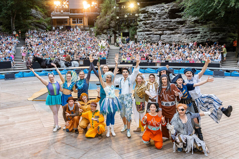 Das "Peter Pan"-Ensemble bei den "Felsenbühnen Festspielen" vor gefüllten Rathener Rängen.