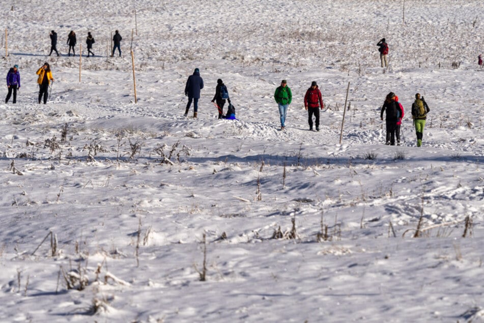 Besucher laufen durch den verschneiten Firstgraben am Spitzingsee, der 1084 Meter über dem Meer liegt.