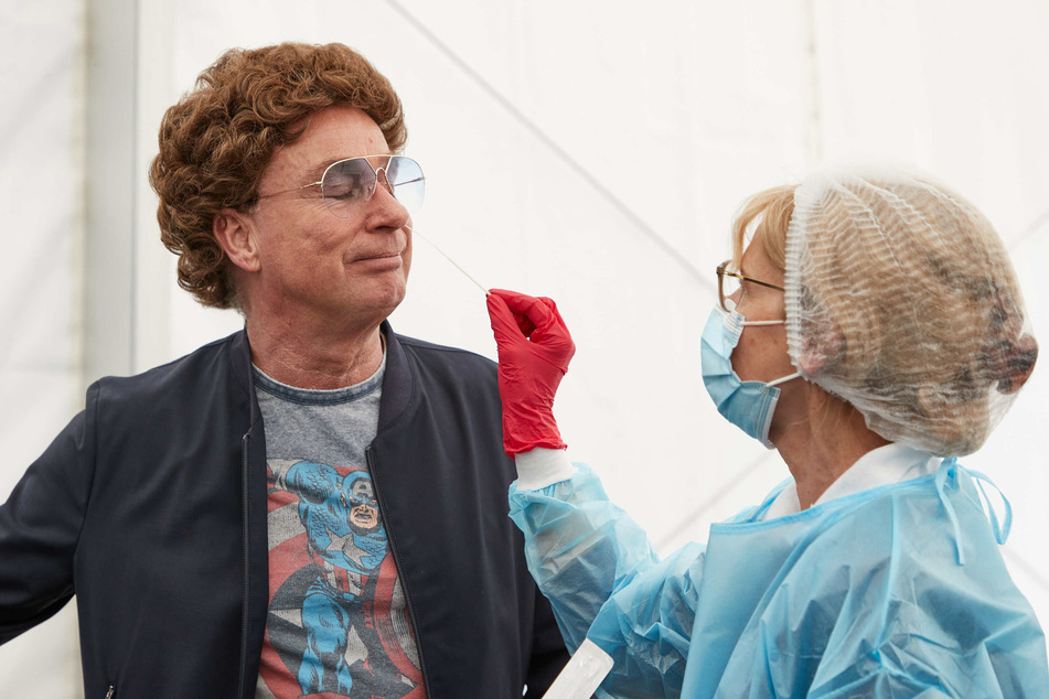 Atze Schröder lässt von Dr. Natasha Schlothauer, Testerin, im Drive-In-Testzentrum an der Barclaycard Arena bei einem Pressetermin einen Nasenabstrich an sich durchführen.
