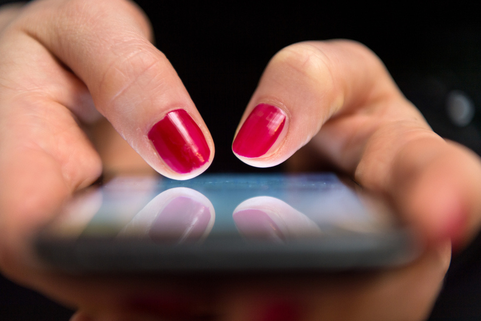 Eine Frau tippt auf ihrem Smartphone (Symbolbild).