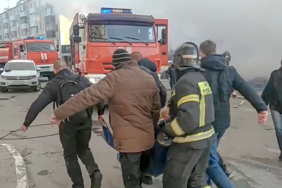 Rettungskräfte und Helfer tragen eine verwundete Person aus der Gefahrenzone in Belgorod.