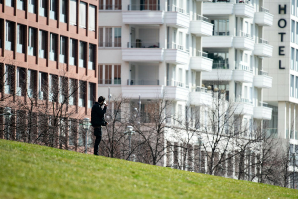Ein Mann steht am Donnerstagnachmittag allein in einem Park am Potsdamer Platz und telefoniert.