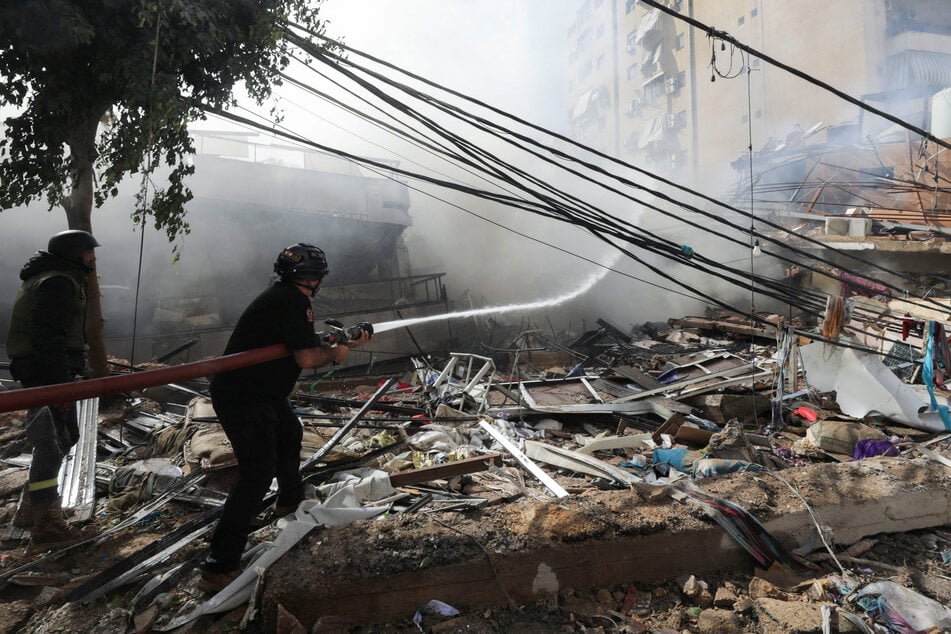 Lebanese civil defense members put out a fire in the aftermath of Israeli strikes on Beirut's southern suburbs on October 20, 2024.