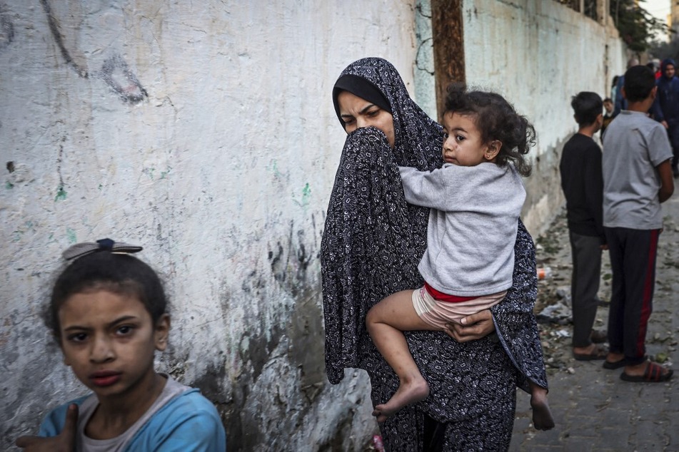 A Palestinian woman holding a child flees following an Israeli airstrike in Rafah in the southern Gaza Strip.
