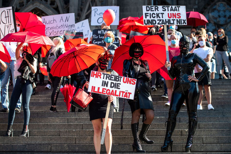 Eine Domina hält während einer Demonstration von Sexarbeiterinnen ein Schild mit der Aufschrift "Der Staat fickt uns und zahlt nix".