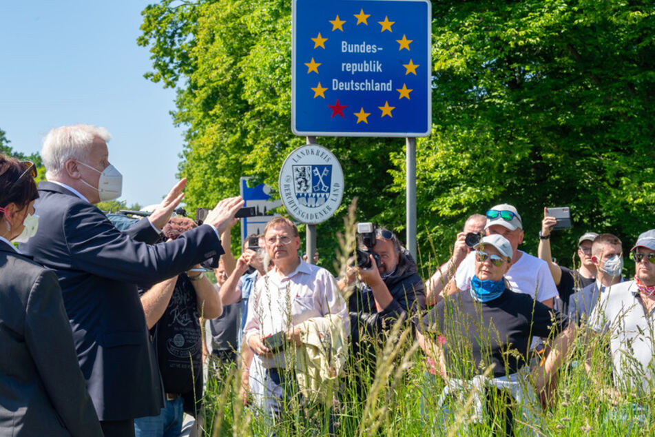 Horst Seehofer (CSU, l), Bundesinnenminister, trägt einen Mundschutz, während er sich am 18. Mai 2020 am bayerischen Grenzübergang Freilassing mit wartenden Anwohnern unterhält.