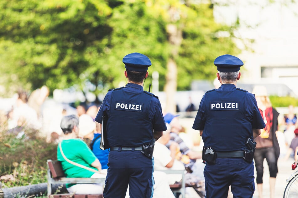 Polizisten stehen in einem Park vor einer Sitzbank. (Symbolbild)