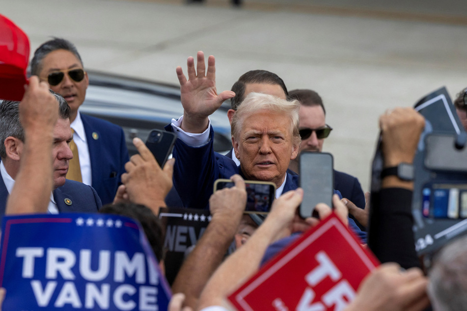 Donald Trump waves to supporters at Wayne County Airport in Romulus, Michigan, on August 20, 2024