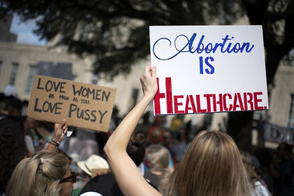 Texans raise signs reading "Abortion Is Healthcare" as they rally against the state's six-week ban in Houston.