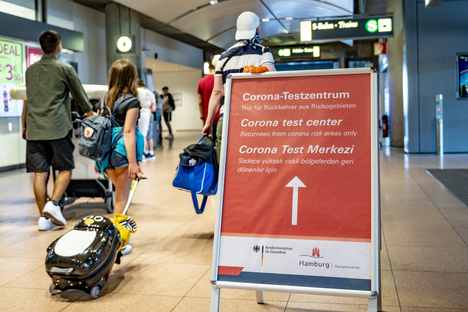 Reisende gehen am Hamburger Flughafen an einem Schild vorbei, auf dem die Richtung zum Corona-Testzentrum angezeigt wird. (Archivbild)