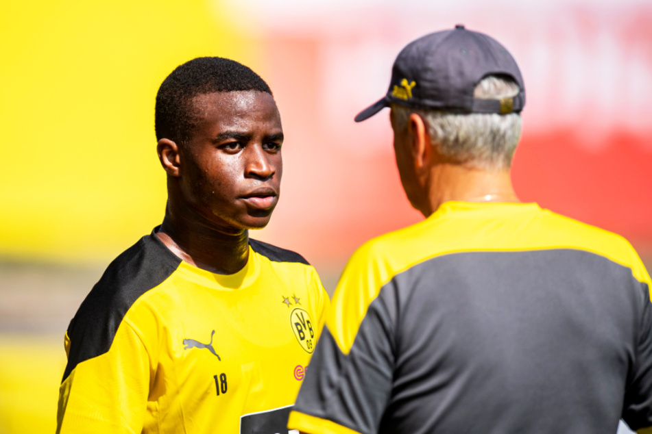 Youssoufa Moukoko (l.) lauscht BVB-Profitrainer Lucien Favre.
