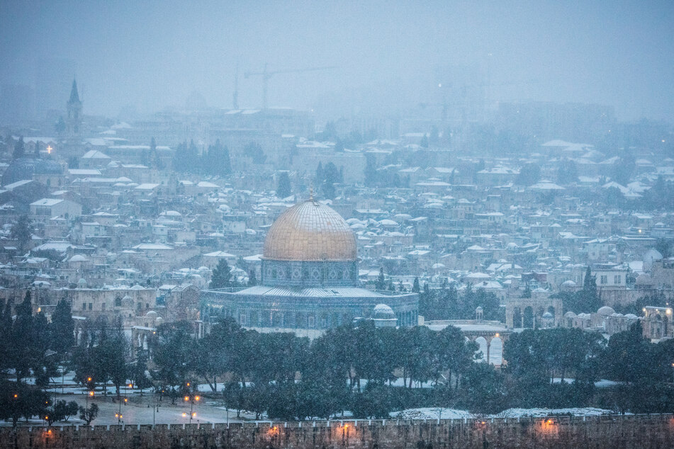 Blick auf den Felsendom in der Altstadt von Jerusalem vom Ölberg aus bei starkem Schneefall.