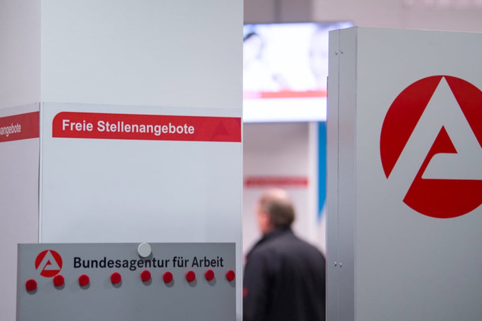 Ein Mann steht im Wartebereich hinter einer Stellwand für Stellenangebote.