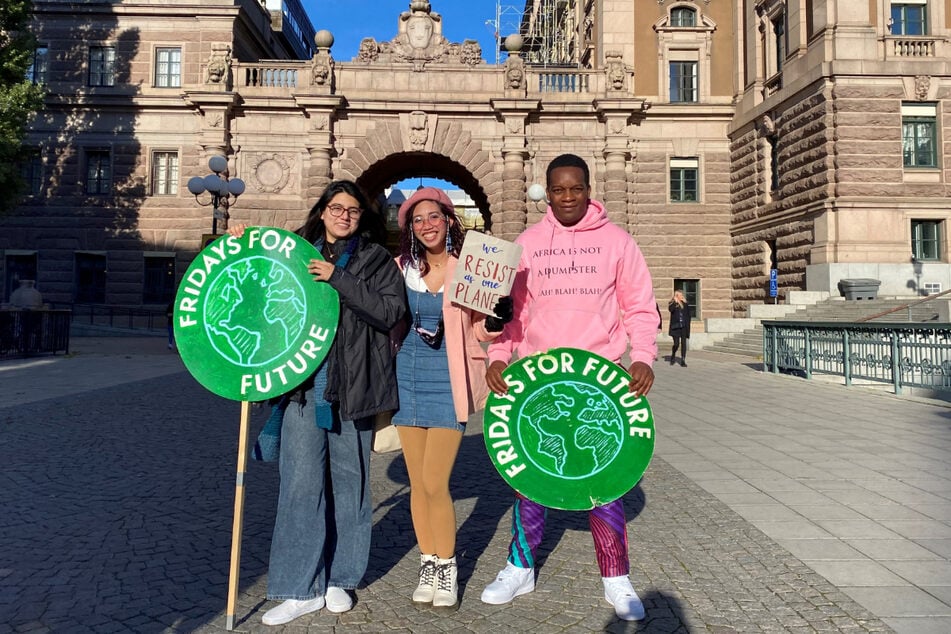 Die Klima-Aktivisten Adriana Calderon aus Mexiko (l.-r.), Mitzi Jonelle Tan von den Philippinen und Kevin Mtai aus Kenia stehen vor dem schwedischen Parlament in Stockholm.