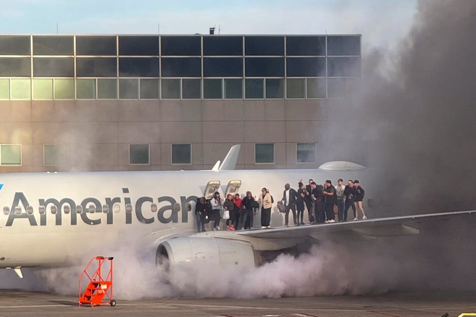 Passengers on an American Airlines jet were forced onto the wing after a fire broke out, lightly injuring 12 people.