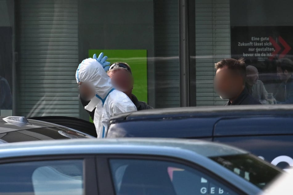 Mit einem weißen Schutzanzug bekleidet wurde der mutmaßliche Täter (20) von Polizeikräften abgeführt.