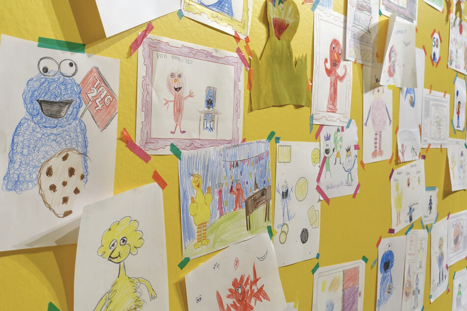 An dieser gelben Wand sammeln sich ganz viele bunte Bilder, die von Kindern und auch Erwachsenen gemalt wurden. In der Ausstellung gibt es einen Tisch mit Papier und Buntstiften an dem man sich kreativ entfalten darf.