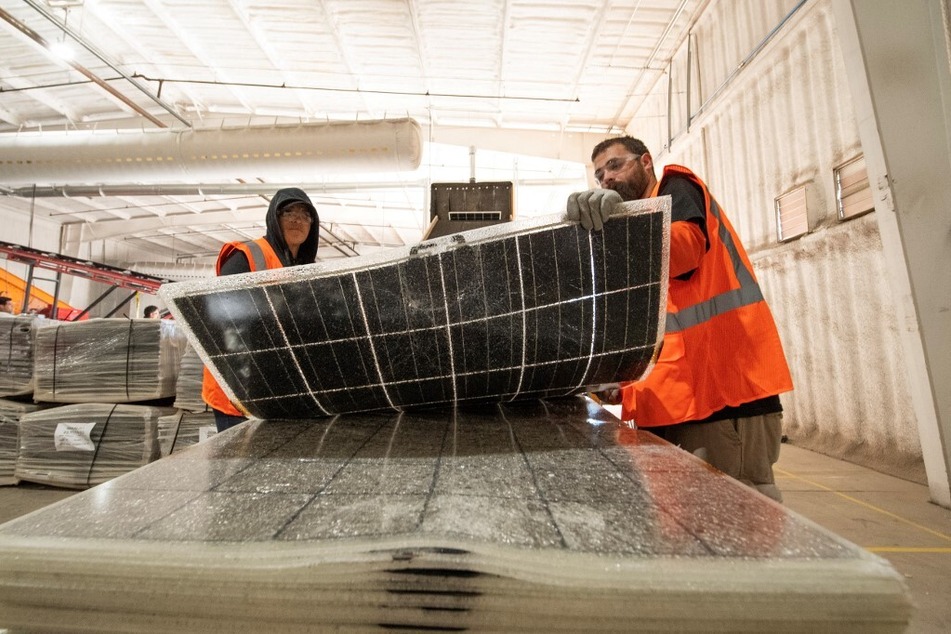 Workers push damaged solar panels into a machine to be recycled at the We Recycle Solar plant in Yuma, Arizona.