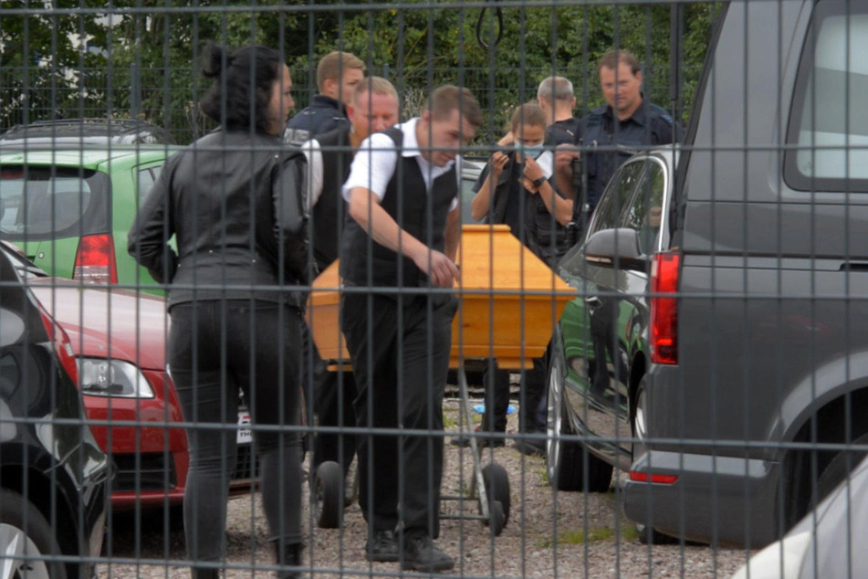 Der 29-Jährige wird in einem Sarg abtransportiert. Er wollte einen Katalysator abmontieren, dabei rutschte der Wagenheber weg und der BMW begrub den Mann.