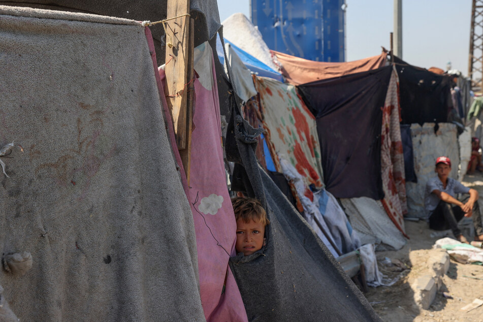 Displaced Palestinians sit by their tents at a makeshift displacement camp set up on a roadside in Deir el-Balah in the central Gaza Strip on Tuesday.